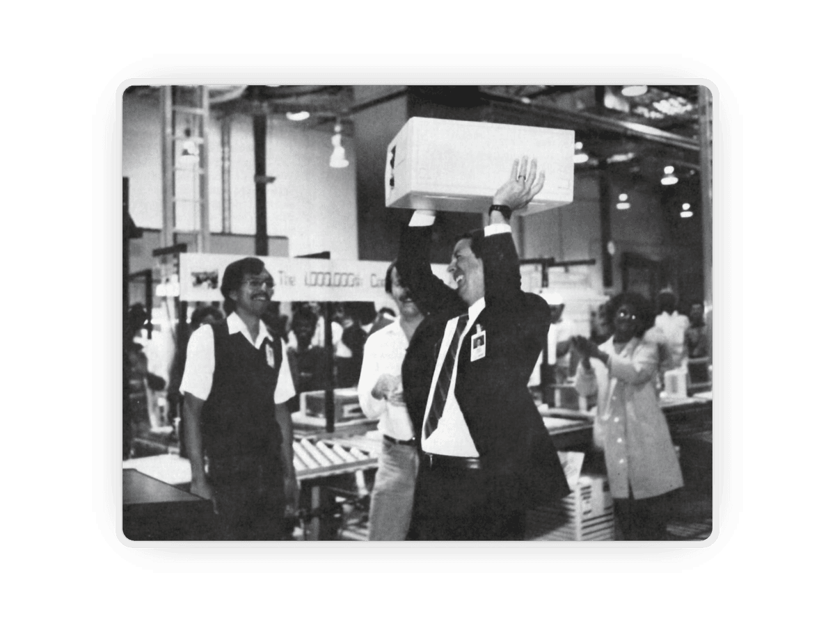 Canion giving the 1 millionth Compaq Portable away to a production line worker. Source: Compaq/Internet Archive.