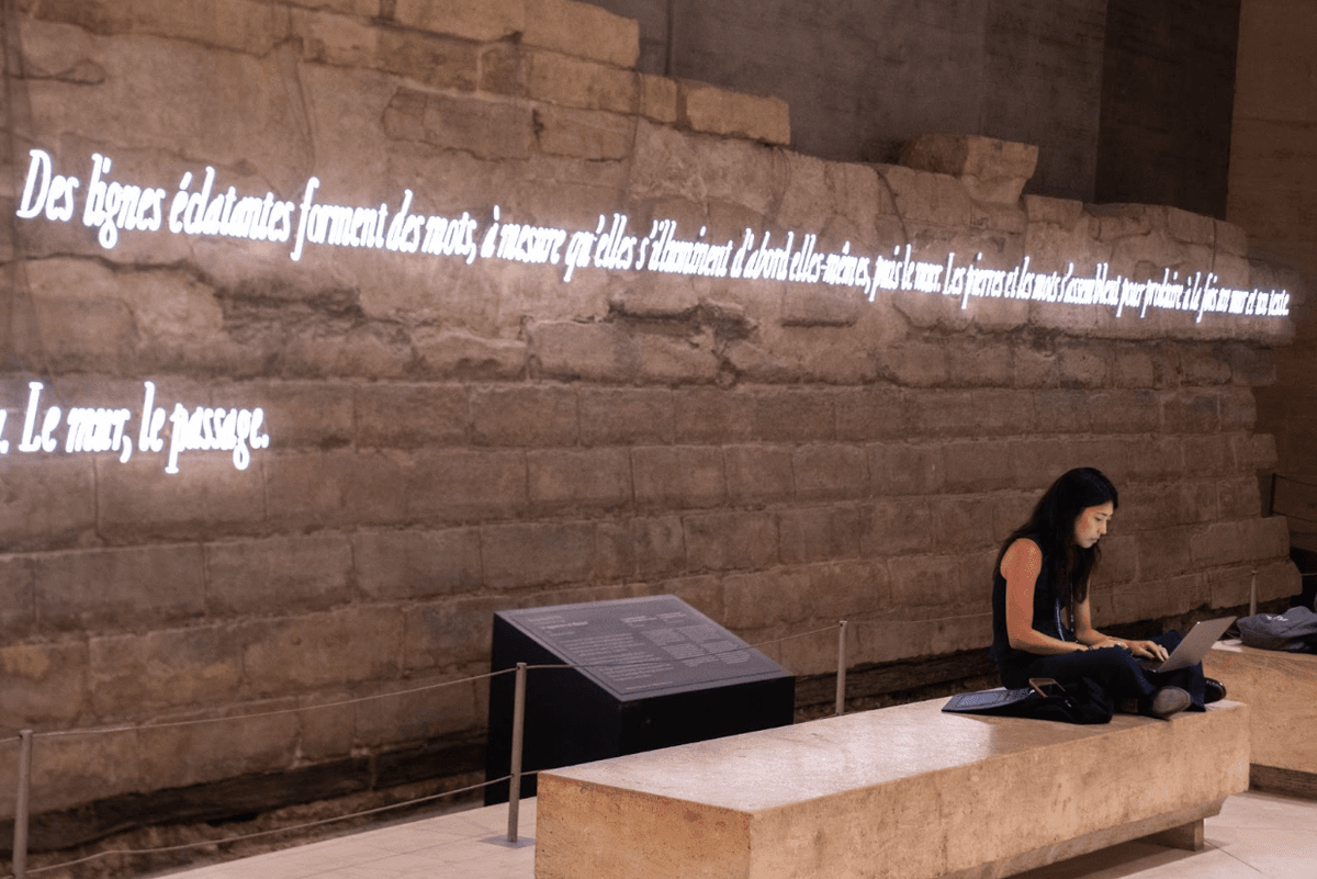 “Brilliant lines form words, as they first illuminate themselves, then the wall. The stones and the words come together to produce both a wall and a text.”